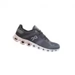 Grauer Sportschuh mit weißer Sohle und einzigartigem, gepolstertem Design. Der Schuh hat ein atmungsaktives Mesh-Obermaterial und eine schwarze Zunge mit einem seitlich sichtbaren Markenlogo.