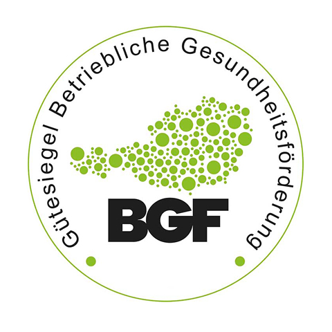 Kreisförmiges Logo mit grünen Punkten in Kartenform, umgeben vom Text „Gütesiegel Betriebliche Gesundheitsförderung“. Die schwarzen Buchstaben „BGF“ stehen zentriert am unteren Rand der Karte.