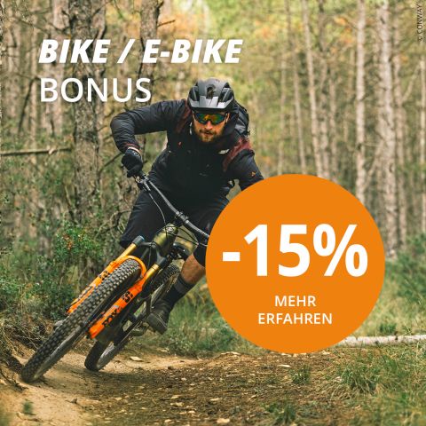 Eine Person fährt mit dem Mountainbike auf einem Pfad in einem Wald und trägt einen Helm und eine Sonnenbrille. Auf dem Bild steht in einem großen orangefarbenen Kreis „Bike/E-Bike Bonus“ und „-15% Mehr Erfahren“.