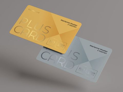 Zwei übereinanderliegende transparente Karten, eine goldene und eine silberne, tragen jeweils die Aufschrift „PLUS CARD“ mit einem geometrischen Muster. Beide zeigen den Namen „Marianne Muster“ und eine Nummer auf neutralem grauem Hintergrund.